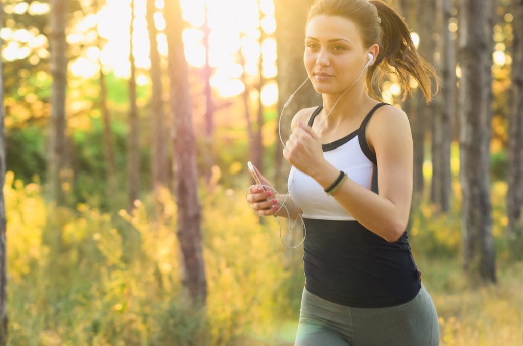 Woman running in the woods. Regular exercise keeps Blood Stasis at bay!