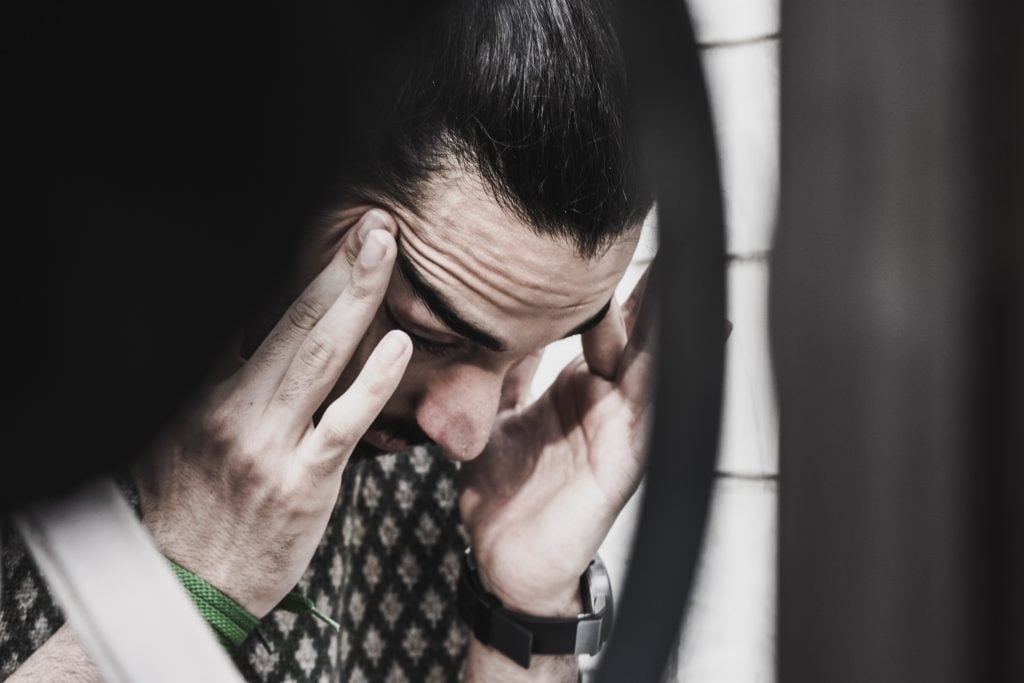 Man holding his temples and looking down.
