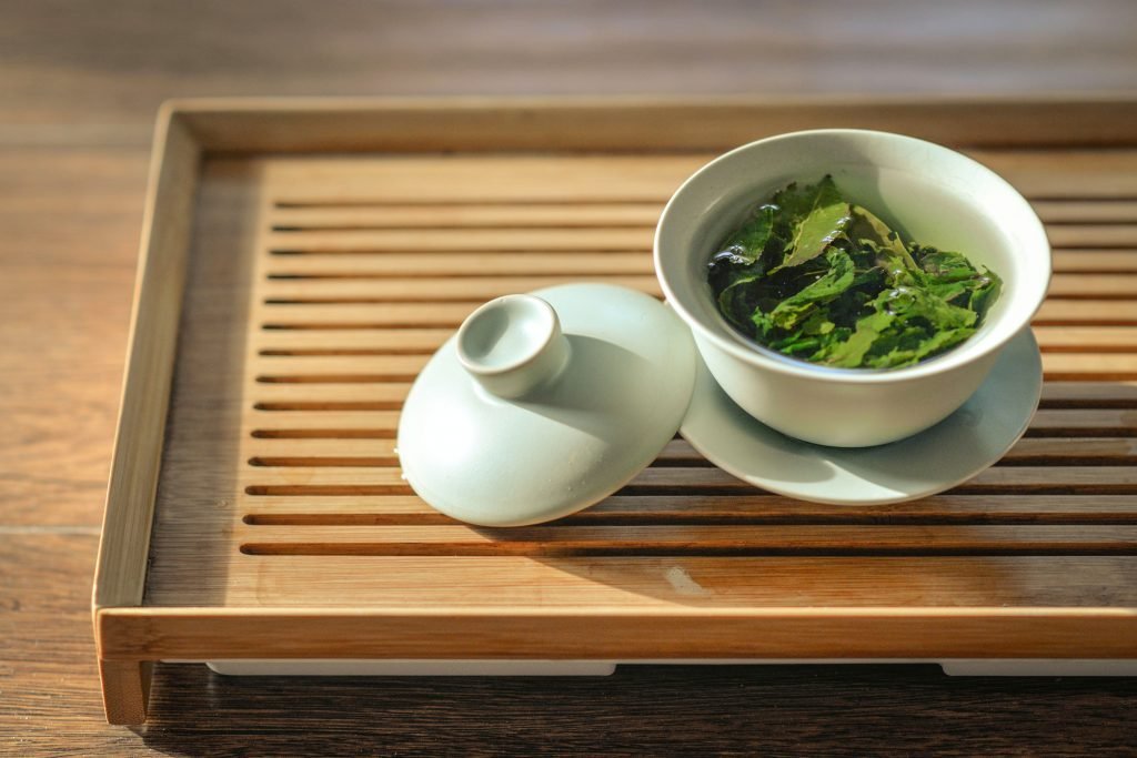 green tea leaves in white ceramic bowl with open lid: may help your body build reserves to cope with fever.