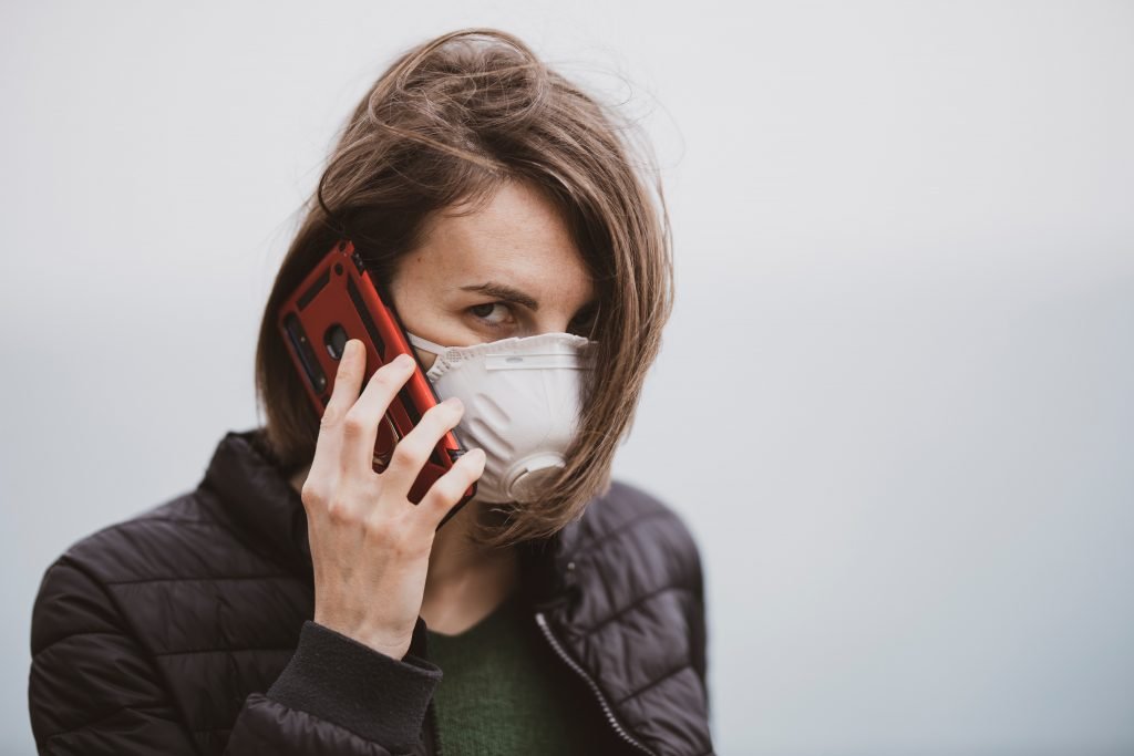 woman in black jacket covering her face with white mask - may help some forms of allergy induced asthma