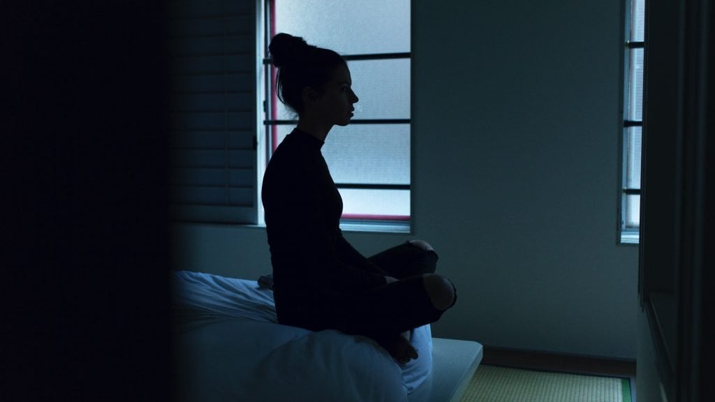 woman sitting on bed: sometimes Blood Stasis causes this.