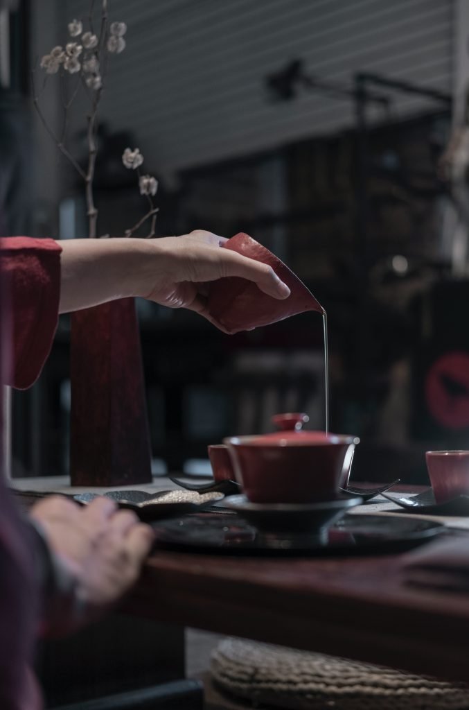 person pouring liquid on cup - tea ceremony for stress