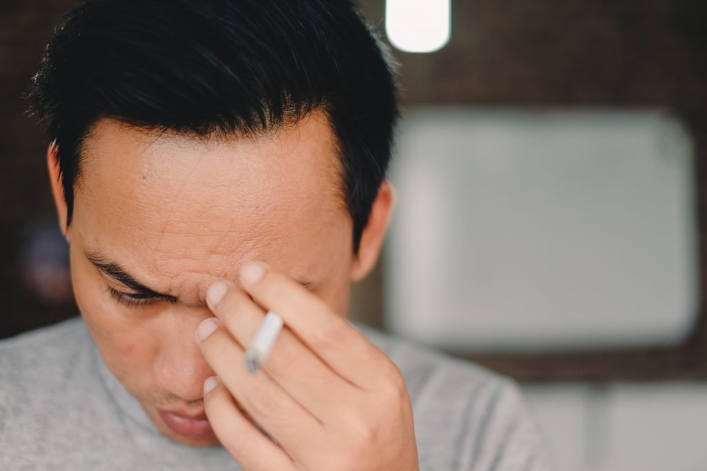 person holding cigarette stick and scratching his face: tense from yin deficiency?