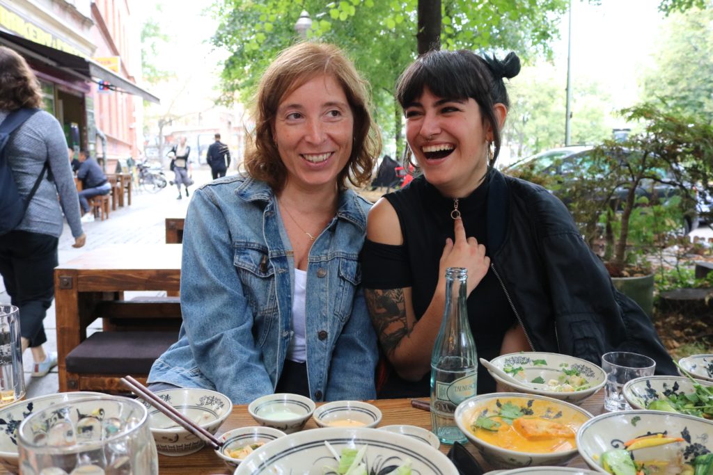 two women sitting on bench at table: eat with people you like and laugh with to help reduce Heart Fire!