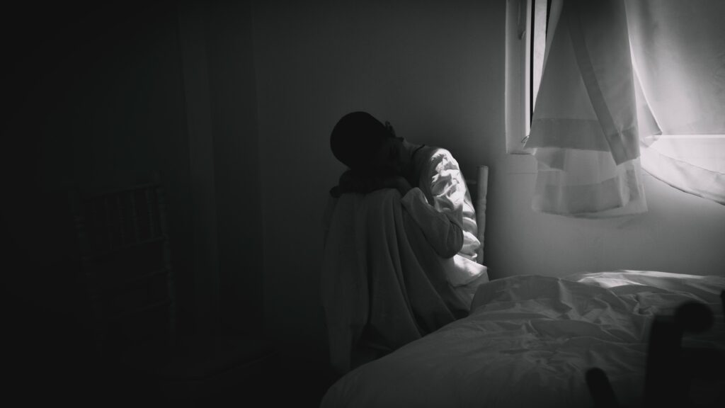 person in gray hoodie sitting on bed: depression, often a mark of a remaining pathogenic factor