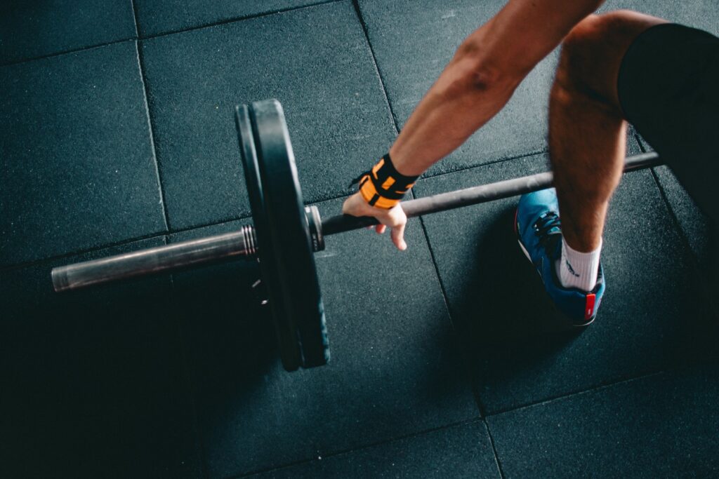 man holding black barbell. Over-exertion can lead to yang deficiency and cold feet.