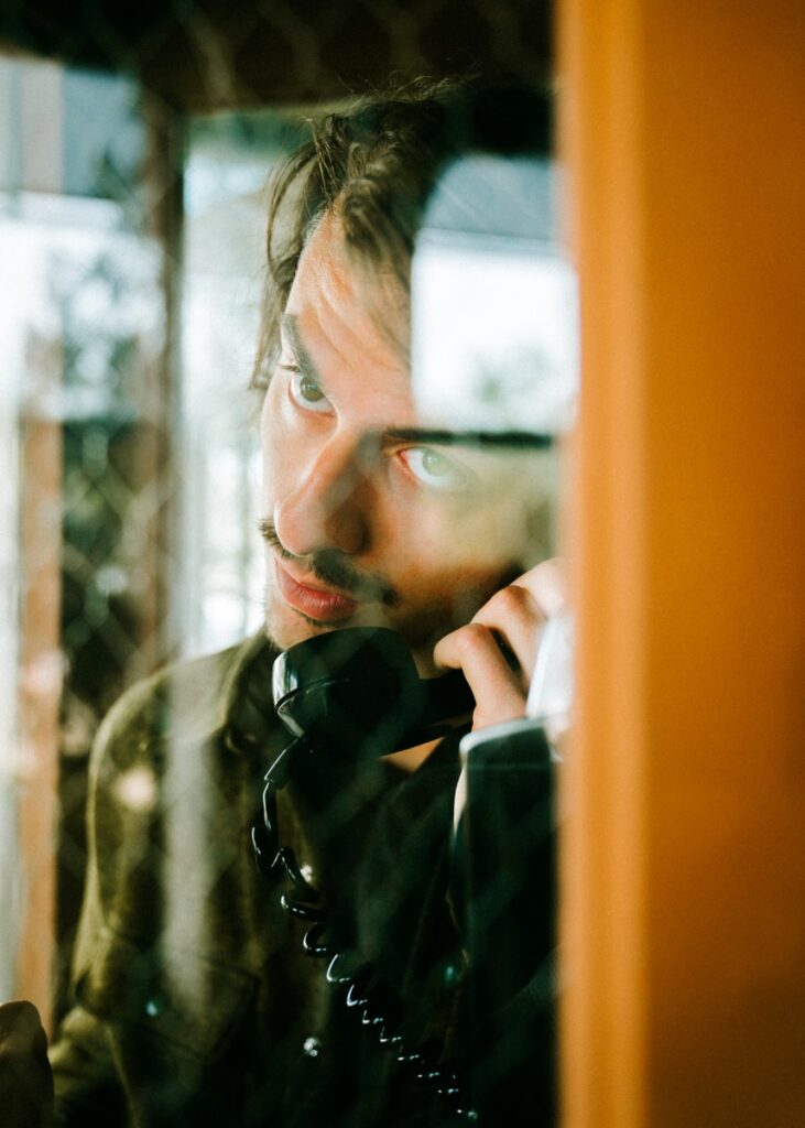 man holding telephone in telephone booth. Impatience, a Wood failing, pushing for growth!