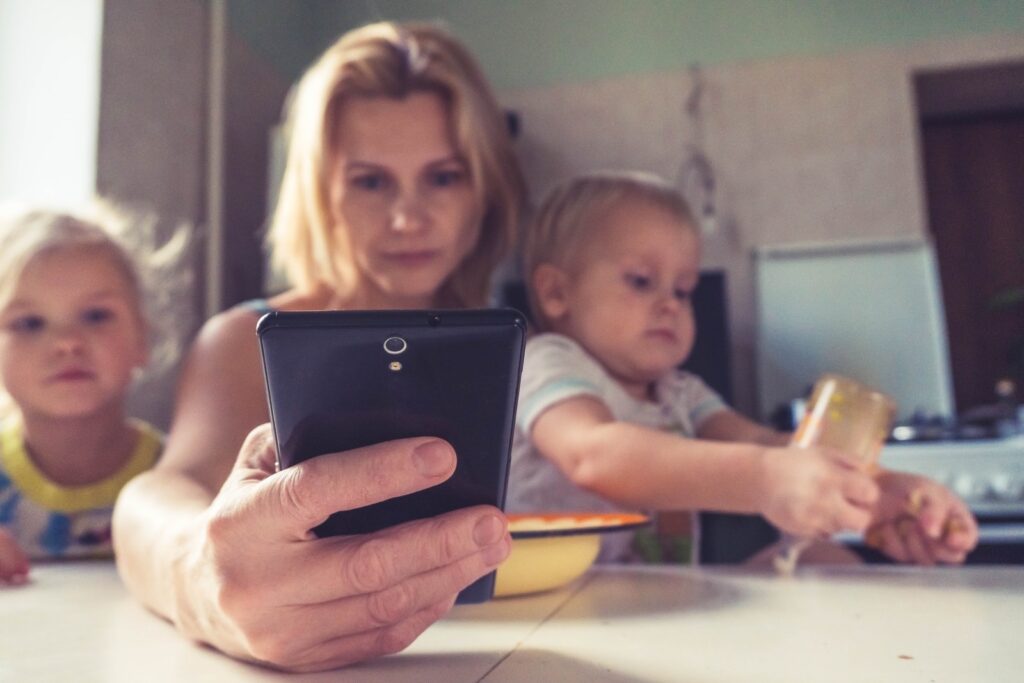 woman in white shirt holding black ipad and 2 kids. Wood element tendencies.