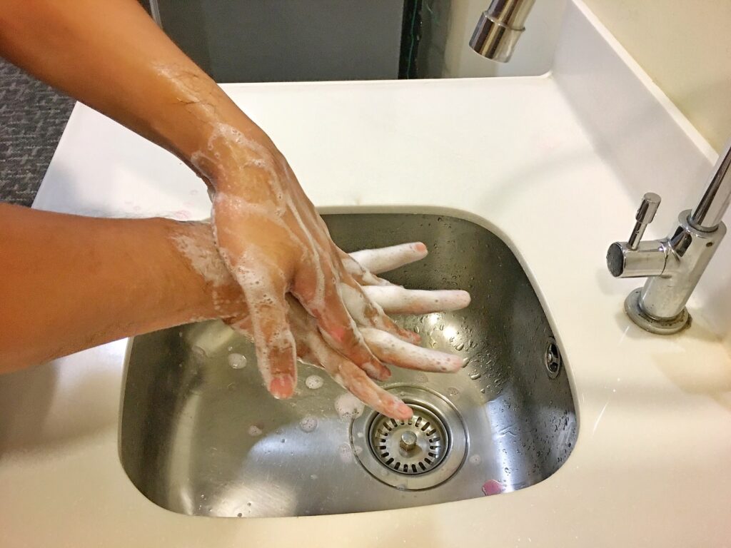person washing hands on sink, to combat infections that might cause erectile dysfunction