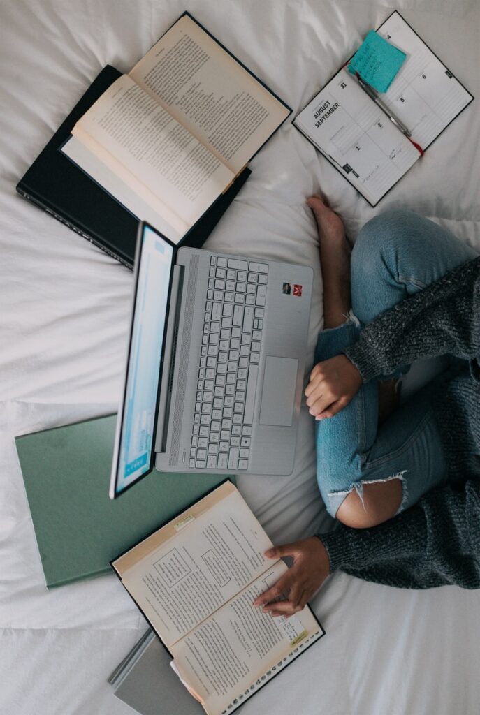 Bowen Research - woman in blue long sleeve shirt and blue denim jeans sitting on bed using laptop