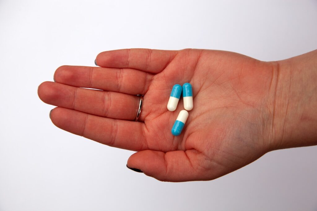 three capsules on person's palm - antibiotics, so easy to take and to quell Qi level Gallbladder heat